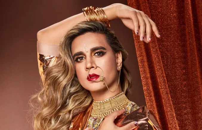 Portrait de Vivek Shraya, lumière et maquillage de couleur chaude et bijoux dorés